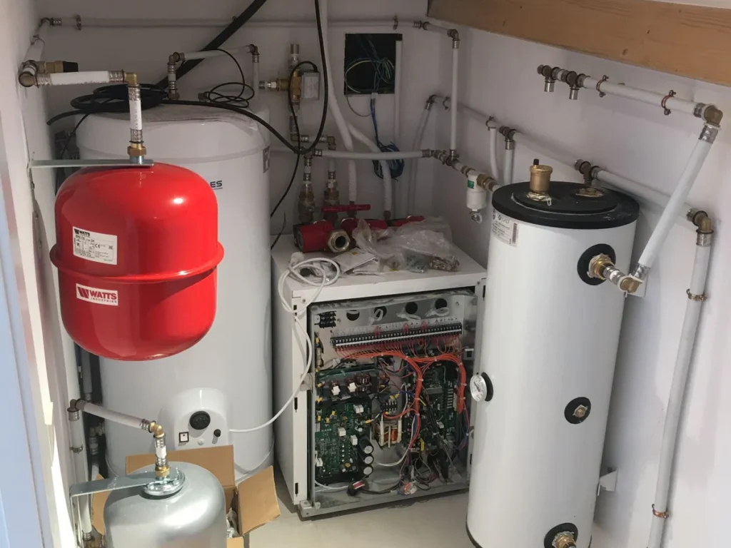 instalación de aerotermia en sala técnica con depósitos de inercia, vaso de expansión y electrónica de control